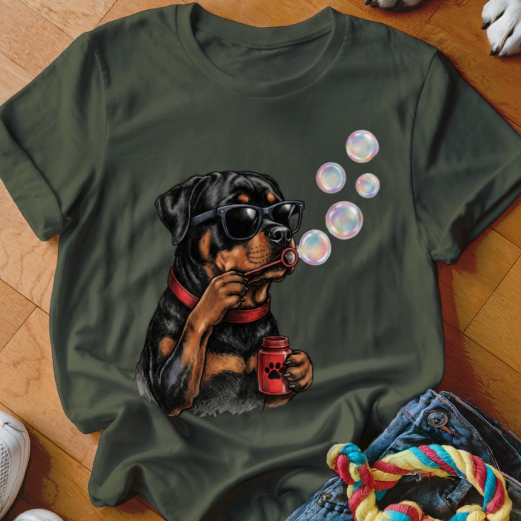 An olive green crewneck t-shirt featuring a graphic of a Rottweiler wearing sunglasses and blowing bubbles.