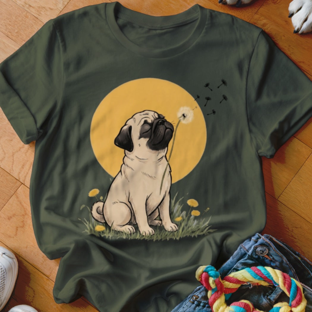 Dark green t-shirt featuring a graphic of a pug sitting in the grass blowing a dandelion.