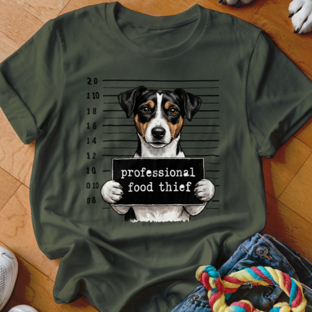 Dog in mugshot holding sign "professional food thief" on olive t-shirt.