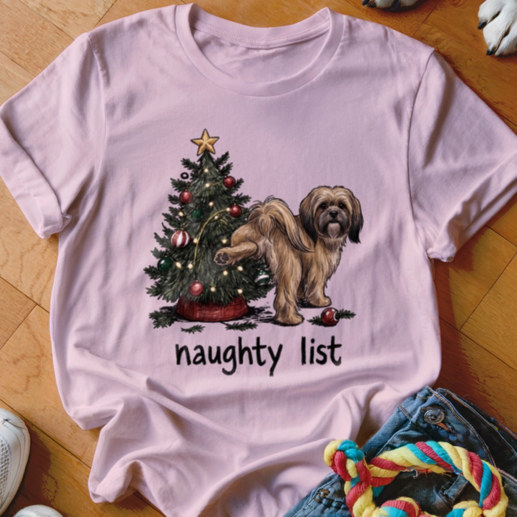 Pink t-shirt with a drawing of a dog by a Christmas tree and the text "naughty list".