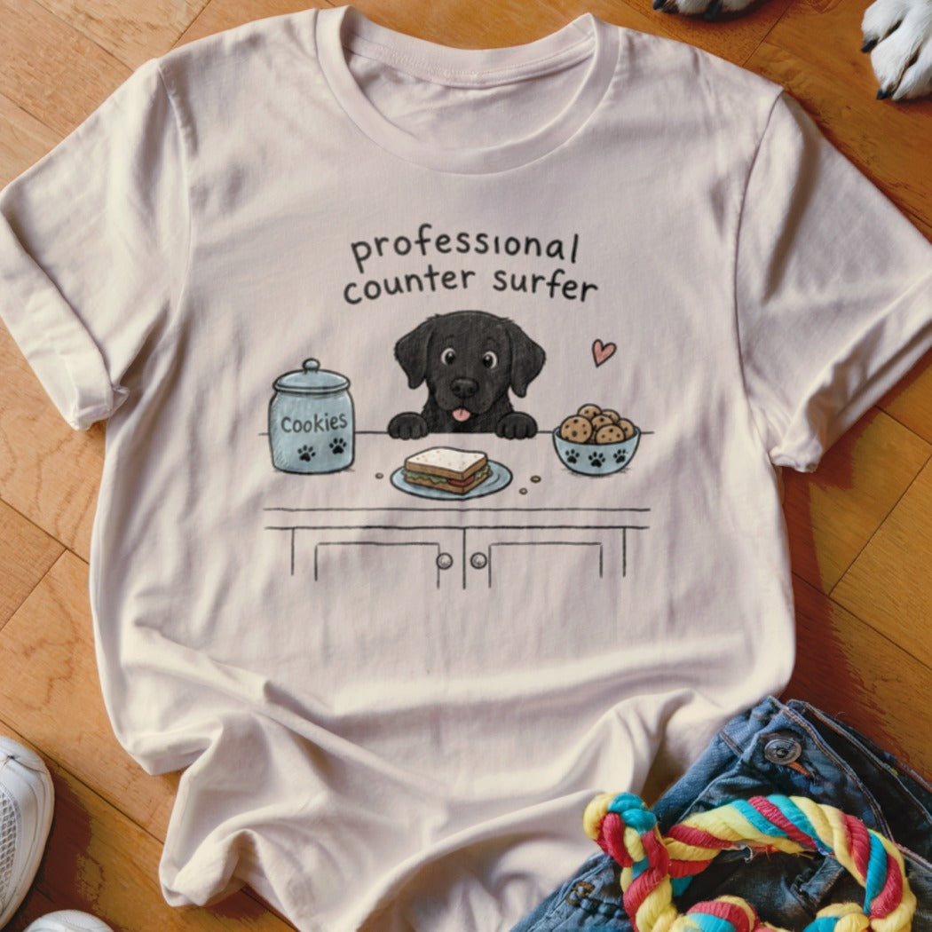 Black lab on a counter with cookies, sandwich, and text "professional counter surfer."