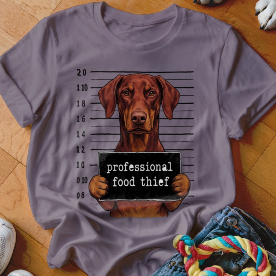 Brown dog mugshot with "professional food thief" sign.