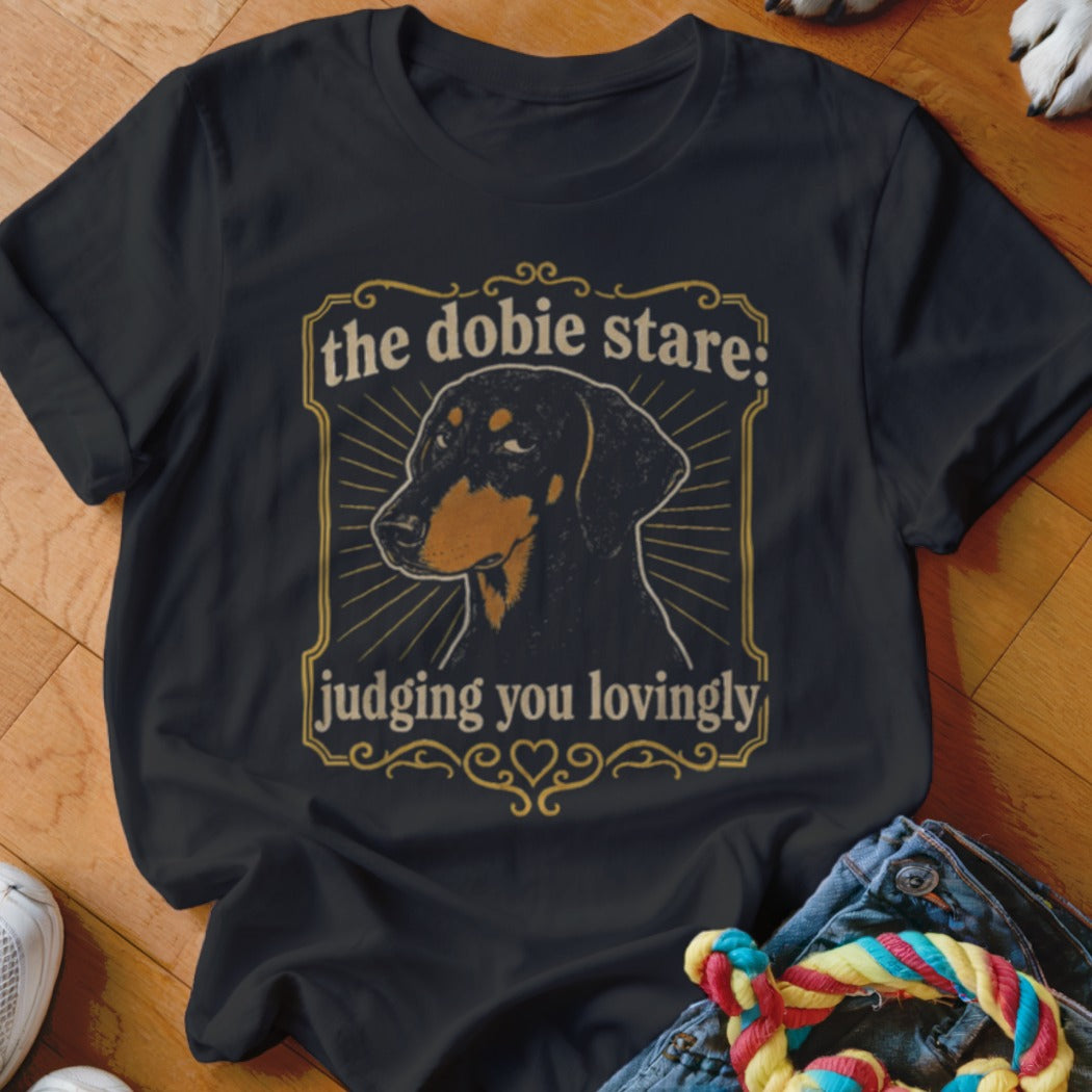 Black t-shirt with a Doberman graphic and text "the dobie stare: judging you lovingly".