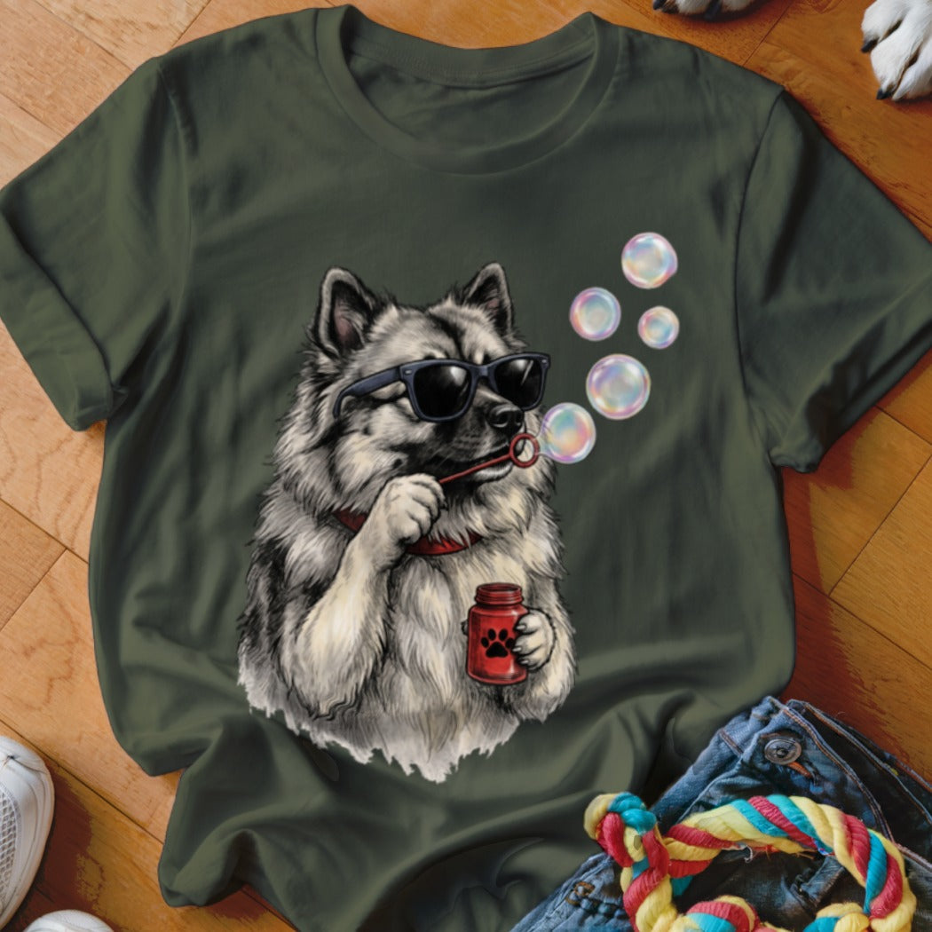 A dark green t-shirt featuring a graphic of a fluffy dog wearing sunglasses while blowing bubbles.