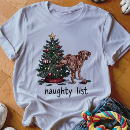 White t-shirt featuring a graphic of a dog lifting its leg on a Christmas tree with the text "naughty list".
