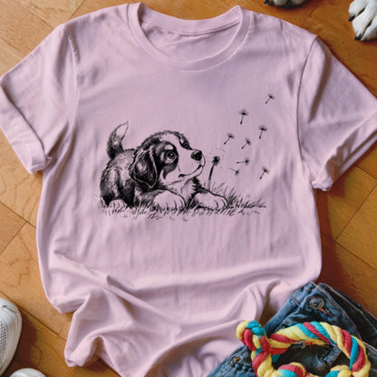 Light pink crewneck t-shirt featuring a black and white graphic of a puppy blowing dandelion seeds.