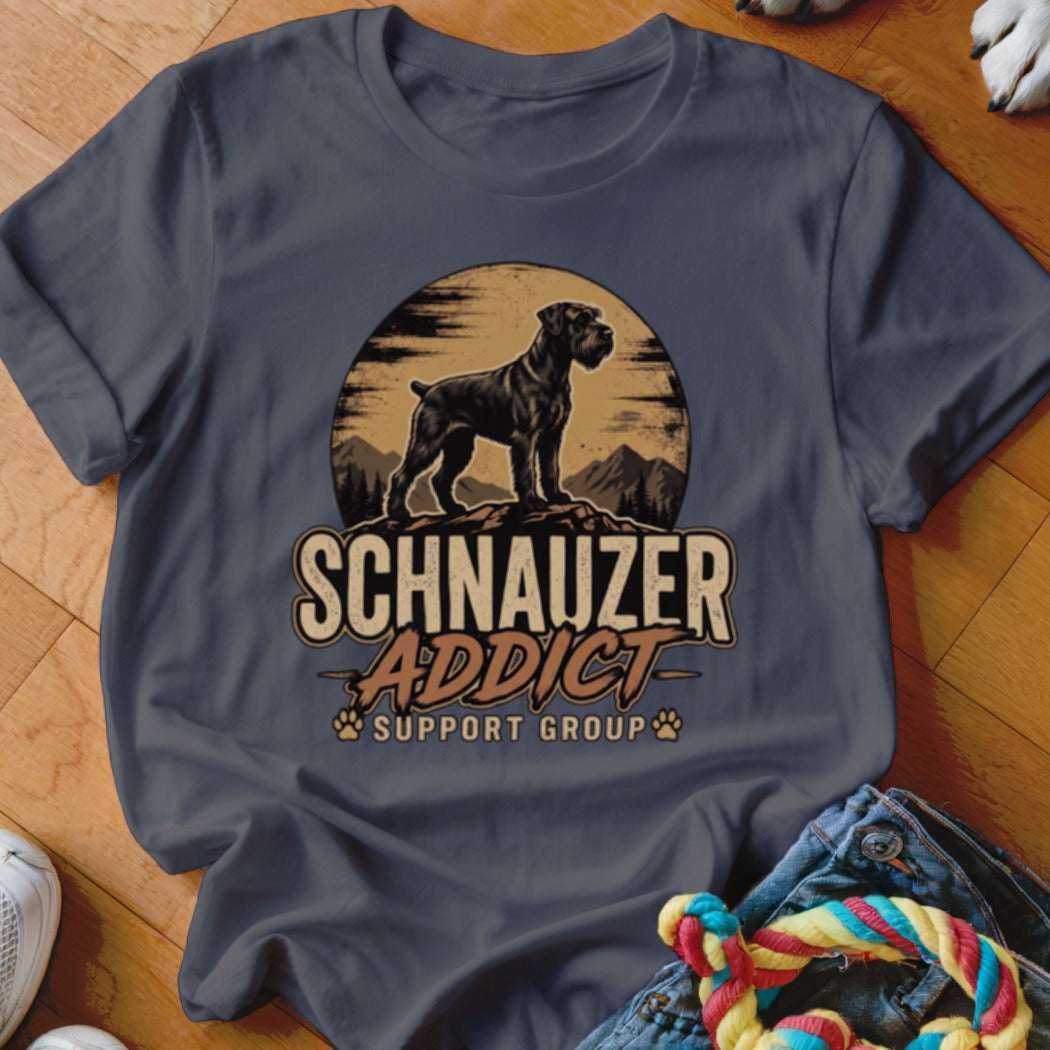 A dark gray t-shirt with a graphic of a Schnauzer standing on a mountain before a sun, featuring the text "Schnauzer Addict Support Group".