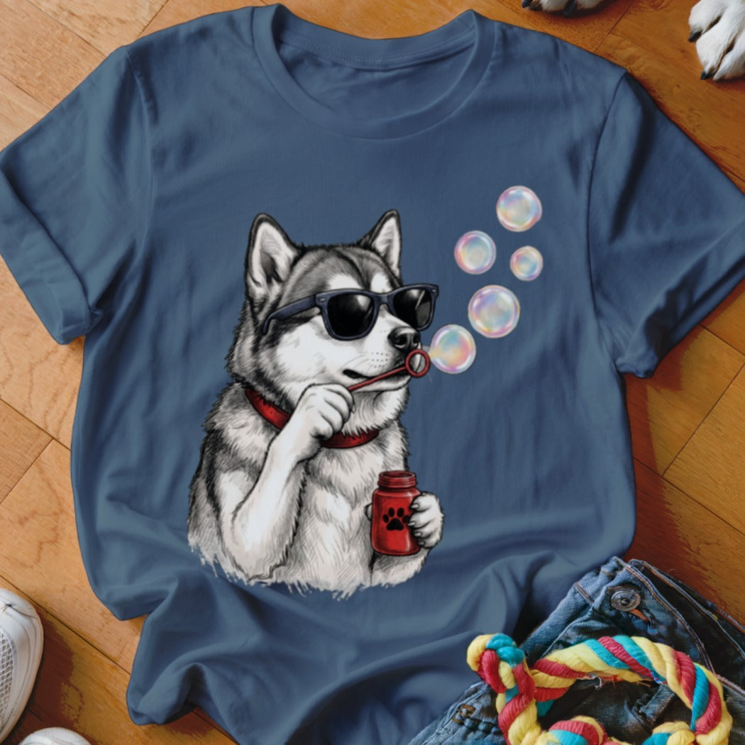A blue t-shirt printed with a graphic of a husky wearing sunglasses and blowing bubbles.