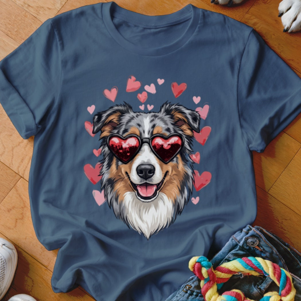 A blue t-shirt features an illustration of an Australian Shepherd wearing heart-shaped sunglasses surrounded by pink hearts.