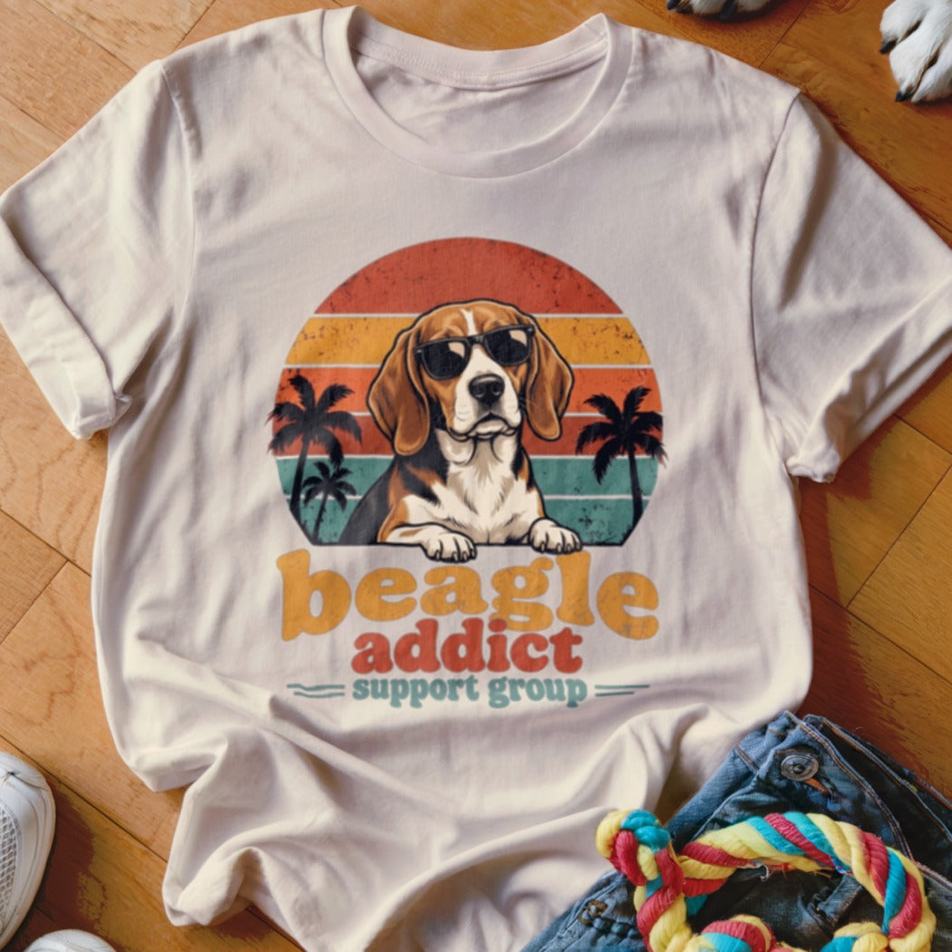 Cream t-shirt featuring a retro graphic of a beagle wearing sunglasses before a sunset and palm trees.
