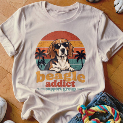 Cream t-shirt featuring a retro graphic of a beagle wearing sunglasses before a sunset and palm trees.