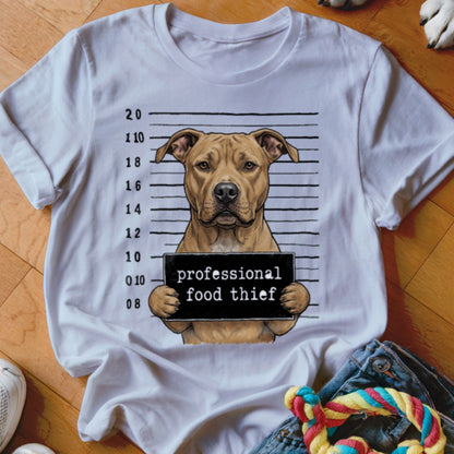 Pit bull dog mugshot with "professional food thief" sign on t-shirt.