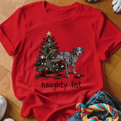 A red t-shirt printed with a Christmas tree, a Dalmatian dog lifting its leg, and the text naughty list.