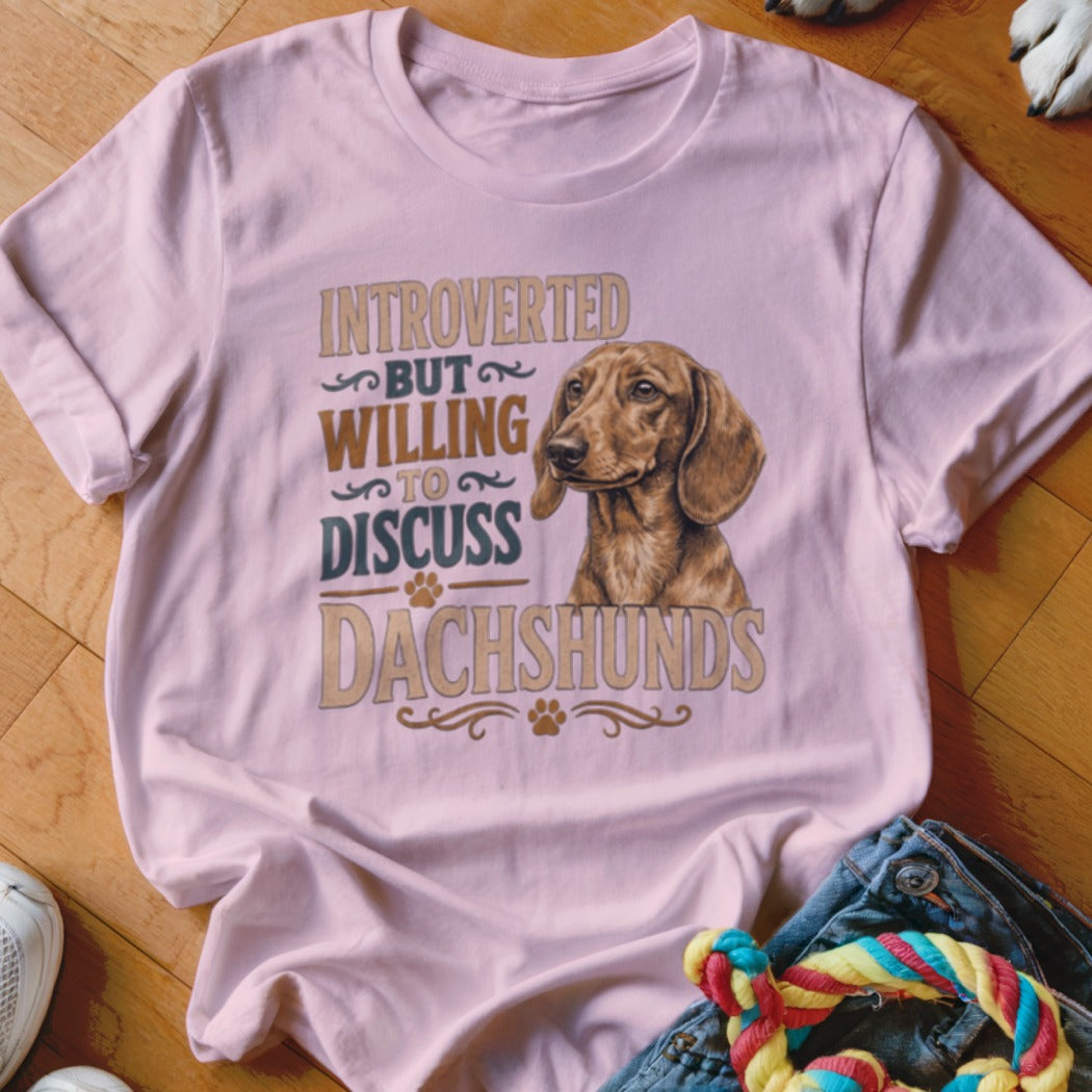 Light pink t-shirt with illustration and text: "Introverted but willing to discuss Dachshunds".