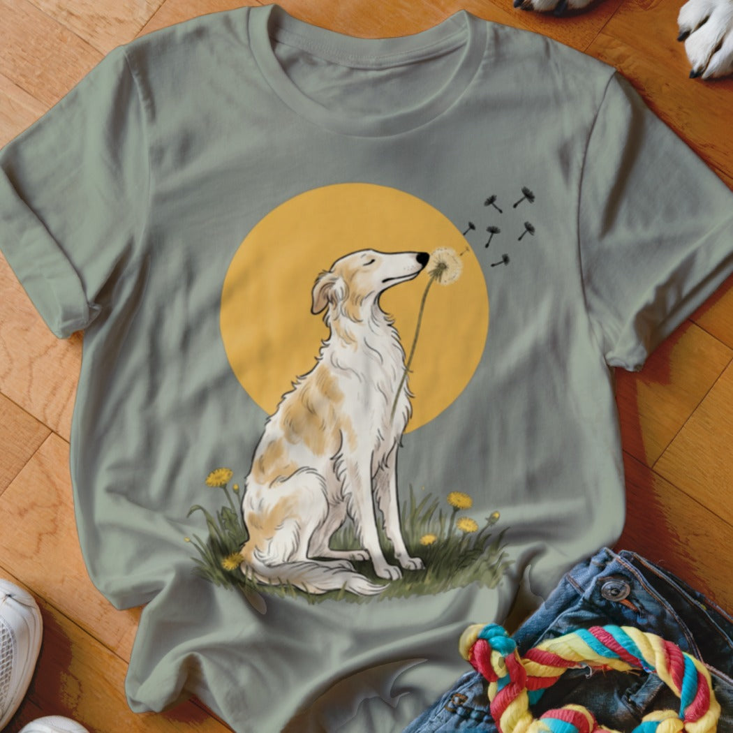 Sage green t-shirt featuring an illustration of a long-snouted dog blowing a dandelion against a yellow circle.