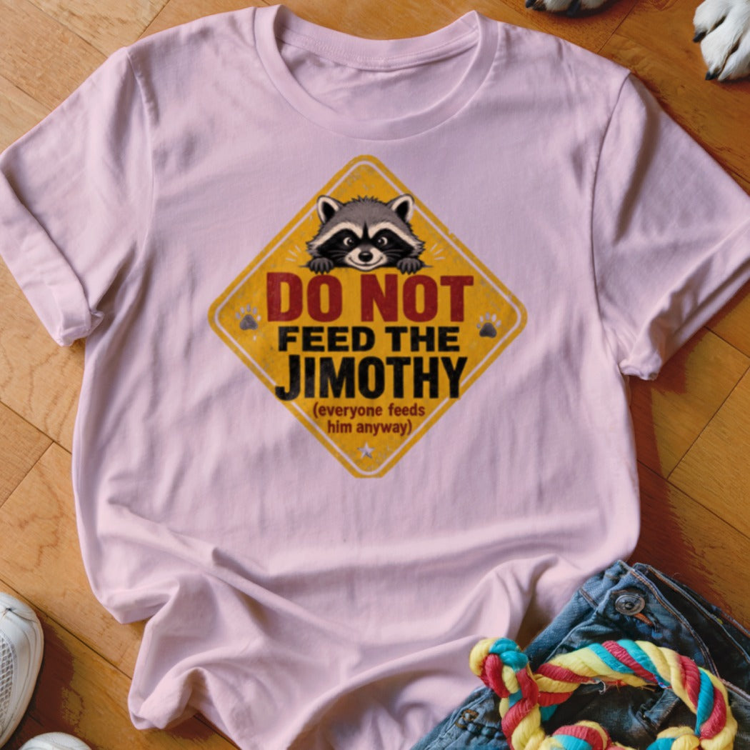 Pink t-shirt with a yellow diamond sign featuring a raccoon and text "DO NOT FEED THE JIMOTHY".