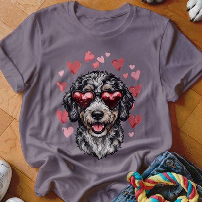 Purple t-shirt featuring a graphic of a curly-haired dog wearing heart-shaped sunglasses surrounded by pink hearts.