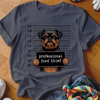 Griffon dog mugshot with "professional food thief" sign on a dark gray t-shirt.