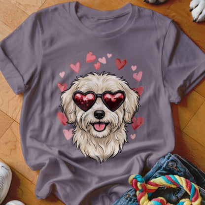 A grey t-shirt featuring a graphic of a fluffy white dog wearing heart-shaped sunglasses surrounded by pink hearts.