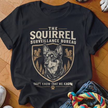 Black t-shirt featuring a graphic of a dog inside a crest with squirrel illustrations and text that reads The Squirrel Surveillance Bureau.