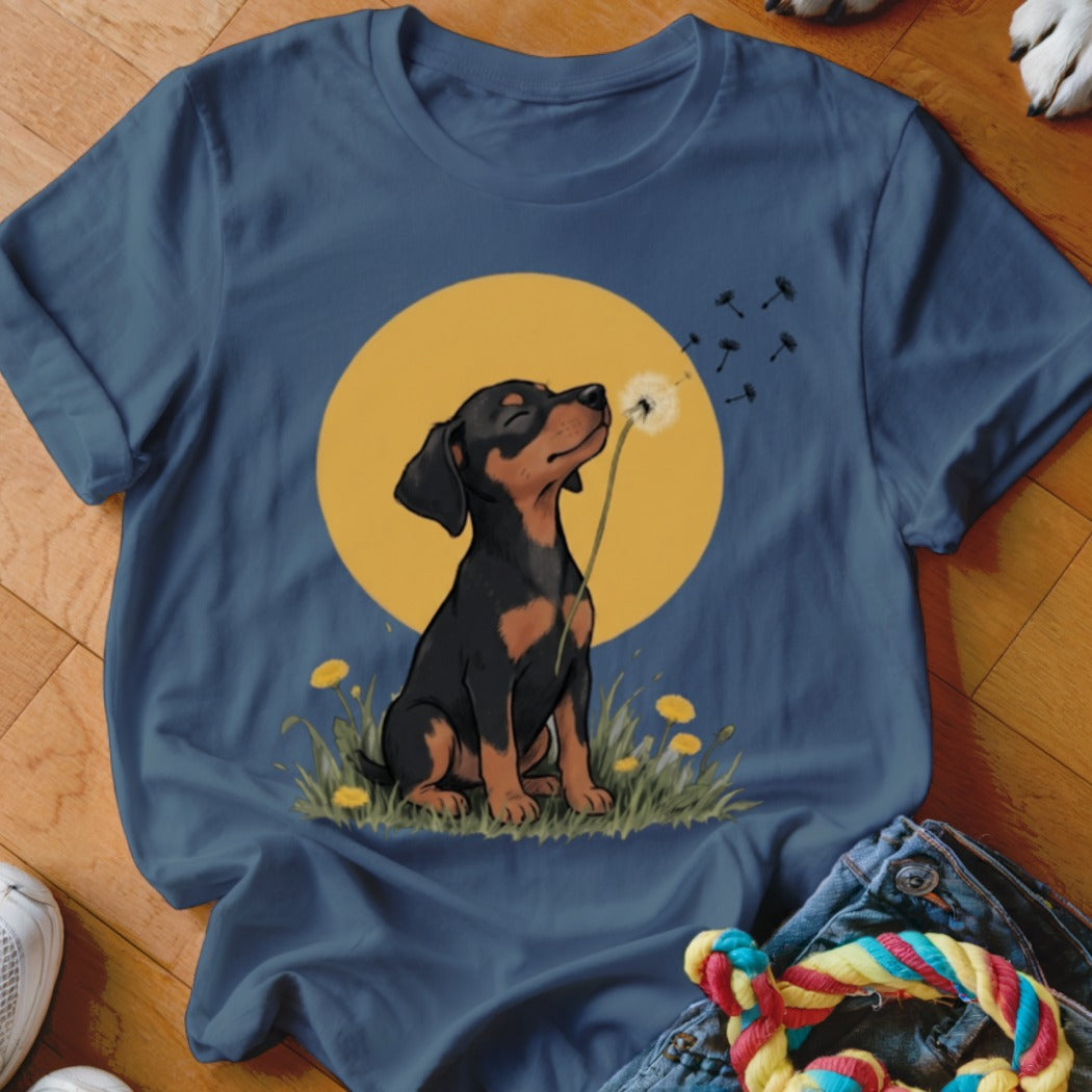 Blue t-shirt featuring an illustration of a black and tan puppy blowing a dandelion seed.