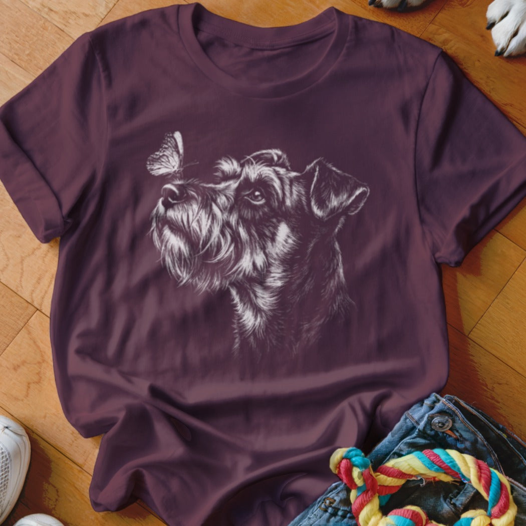 A dark purple t-shirt featuring a white line drawing of a terrier and butterfly on wood flooring.