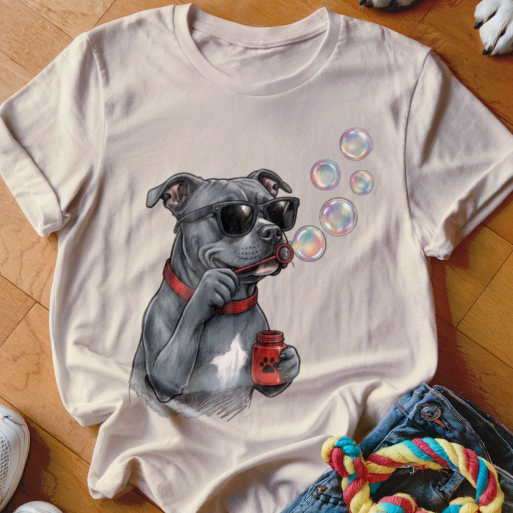 A light-colored t-shirt featuring an illustrated graphic of a pit bull wearing sunglasses and blowing bubbles.