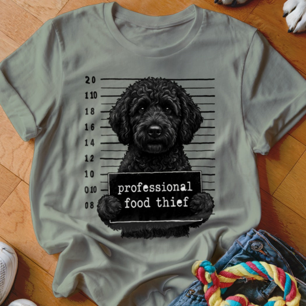 Black dog mugshot with "professional food thief" sign.
