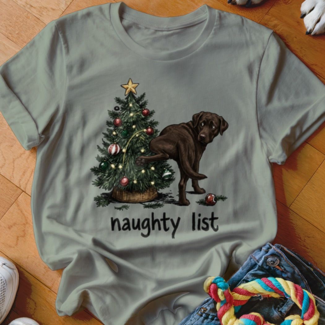 Chocolate lab lifting leg on Christmas tree with "naughty list" text.