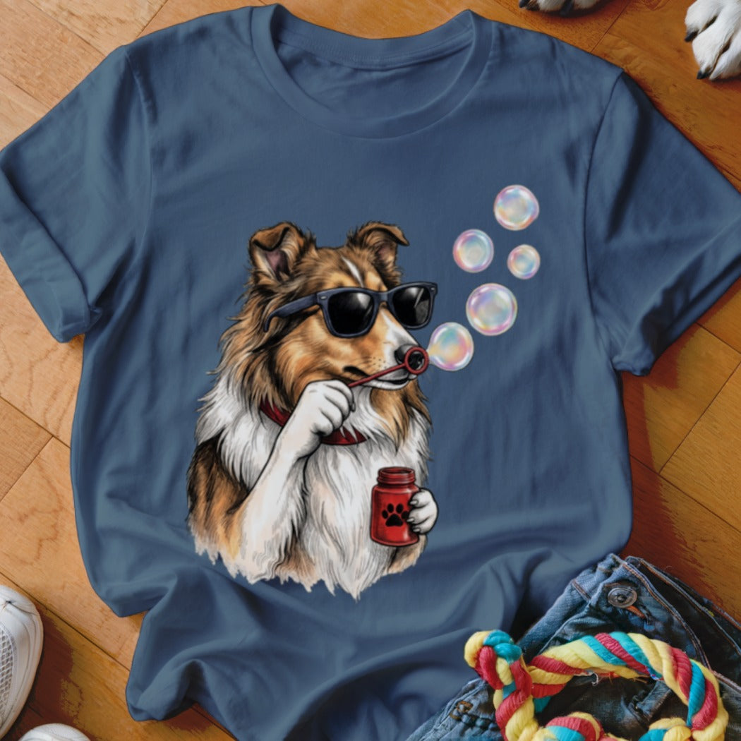 Blue t-shirt featuring an illustration of a Sheltie dog wearing sunglasses and blowing bubbles.