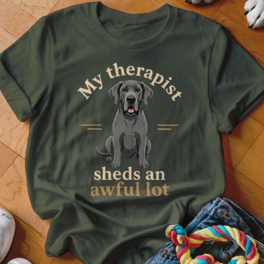 Great Dane sitting on a dark green t-shirt with text "My therapist sheds an awful lot".