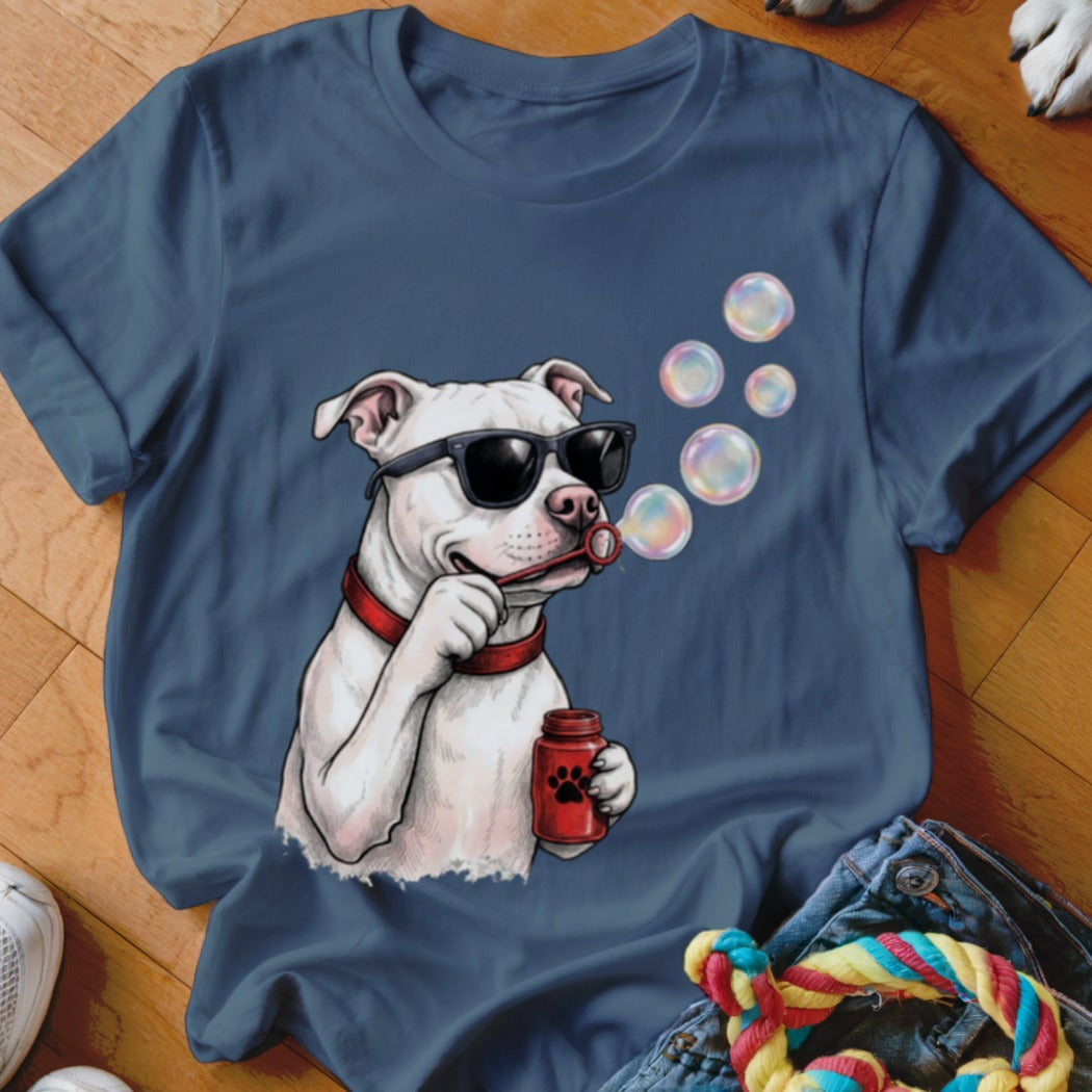 A blue t-shirt featuring an illustrated white dog wearing sunglasses and blowing soap bubbles.