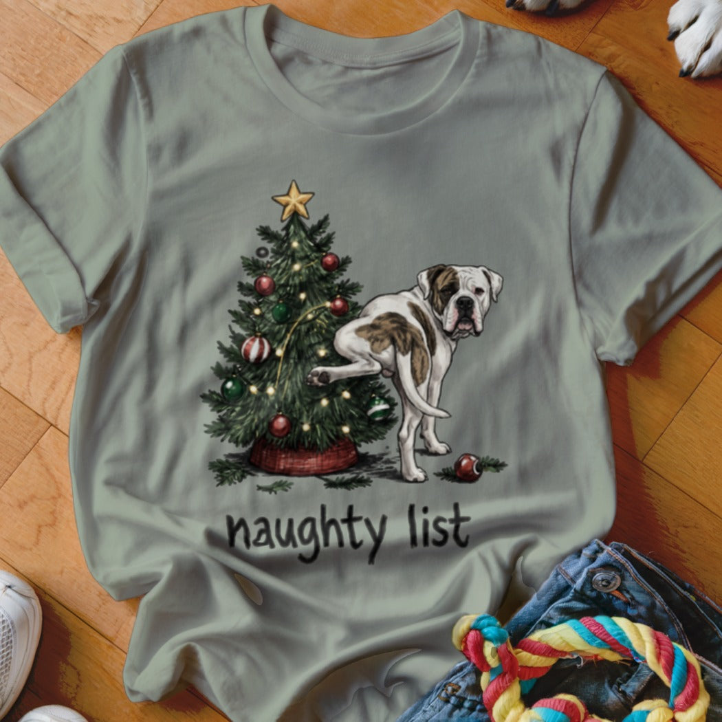 Dog lifting leg at Christmas tree with text "naughty list" on shirt.