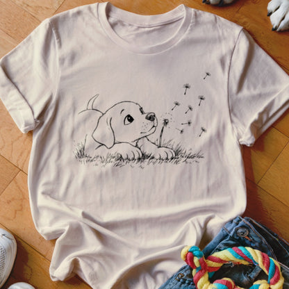 Light pink t-shirt featuring a black line drawing of a puppy playing with dandelion seeds.
