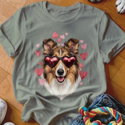 Sage green t-shirt featuring a graphic of a Sheltie dog wearing heart-shaped sunglasses surrounded by pink hearts.
