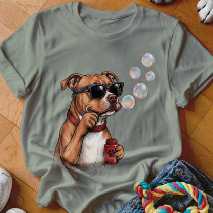 Sage green t-shirt featuring a graphic of a brown dog wearing sunglasses and blowing soap bubbles.