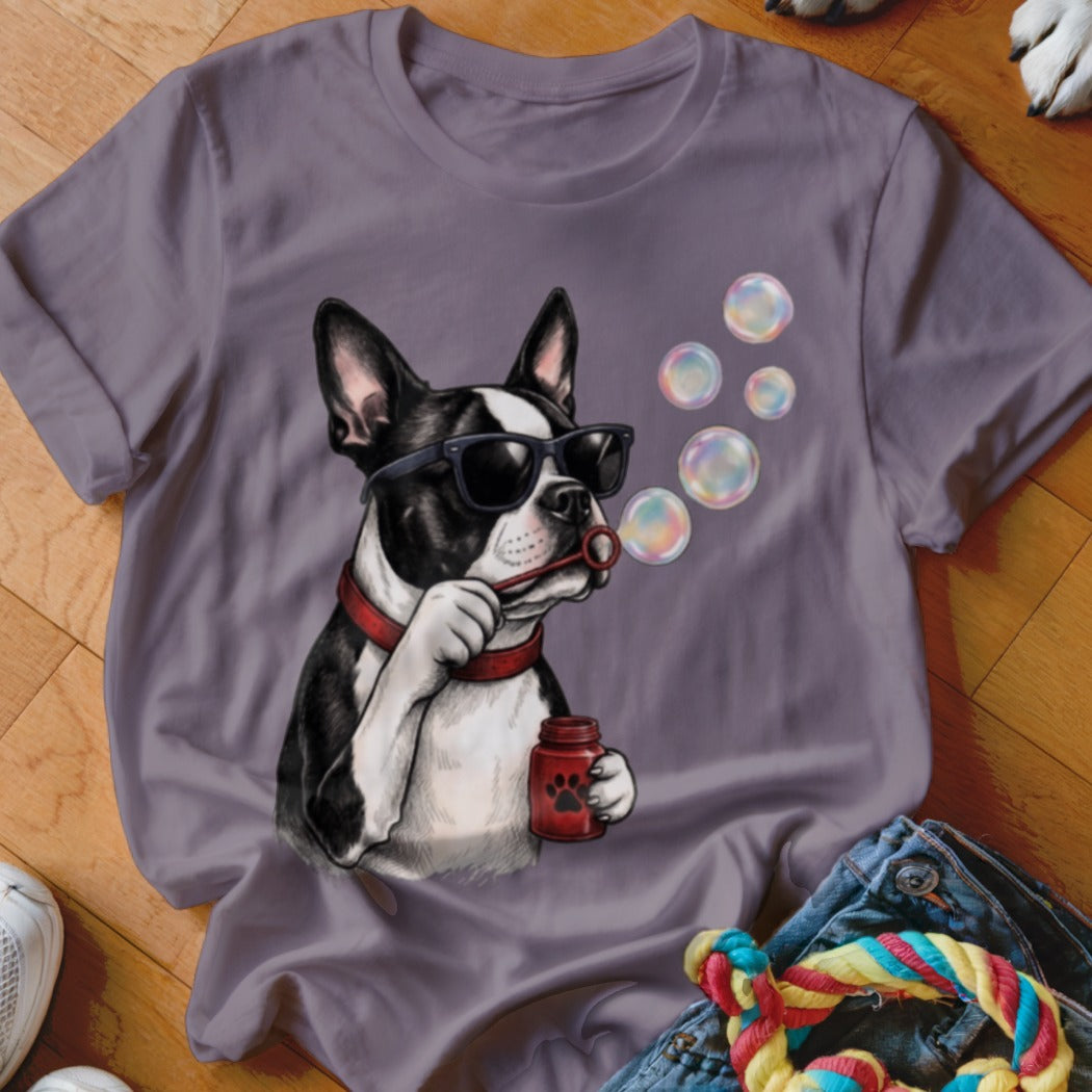 A purple t-shirt featuring an illustration of a Boston terrier wearing sunglasses and blowing soap bubbles.