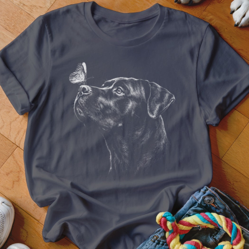 A dark gray crewneck t-shirt featuring a white sketch graphic of a Rottweiler looking at a butterfly on its nose.