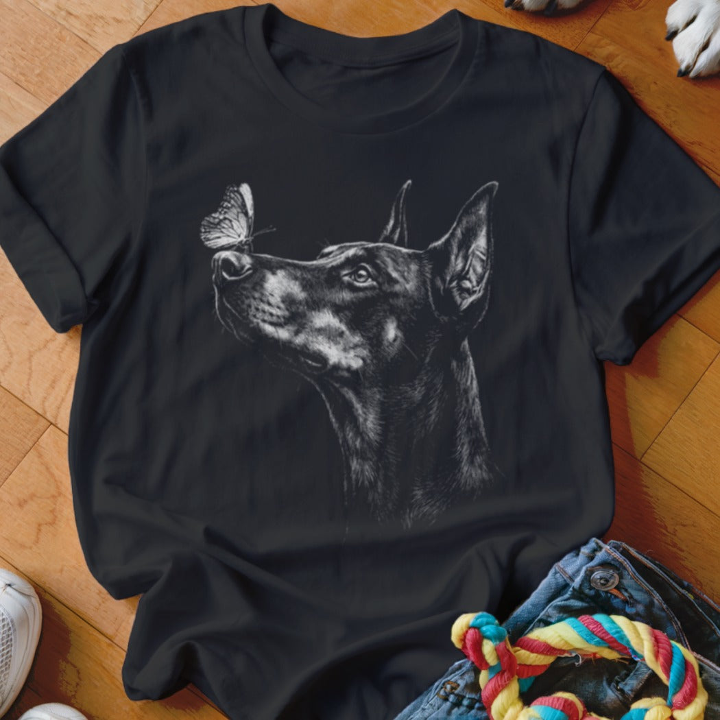 Black t-shirt featuring a white line drawing of a Doberman Pinscher looking at a butterfly on its nose.
