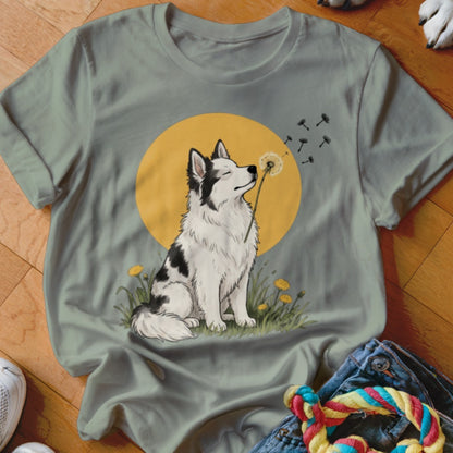 A grey crewneck t-shirt featuring an illustration of a black and white dog blowing dandelion seeds.
