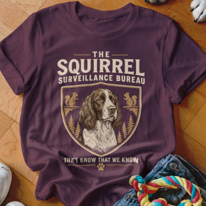 Maroon t-shirt featuring a dog graphic, text reading The Squirrel Surveillance Bureau, and a shield crest.