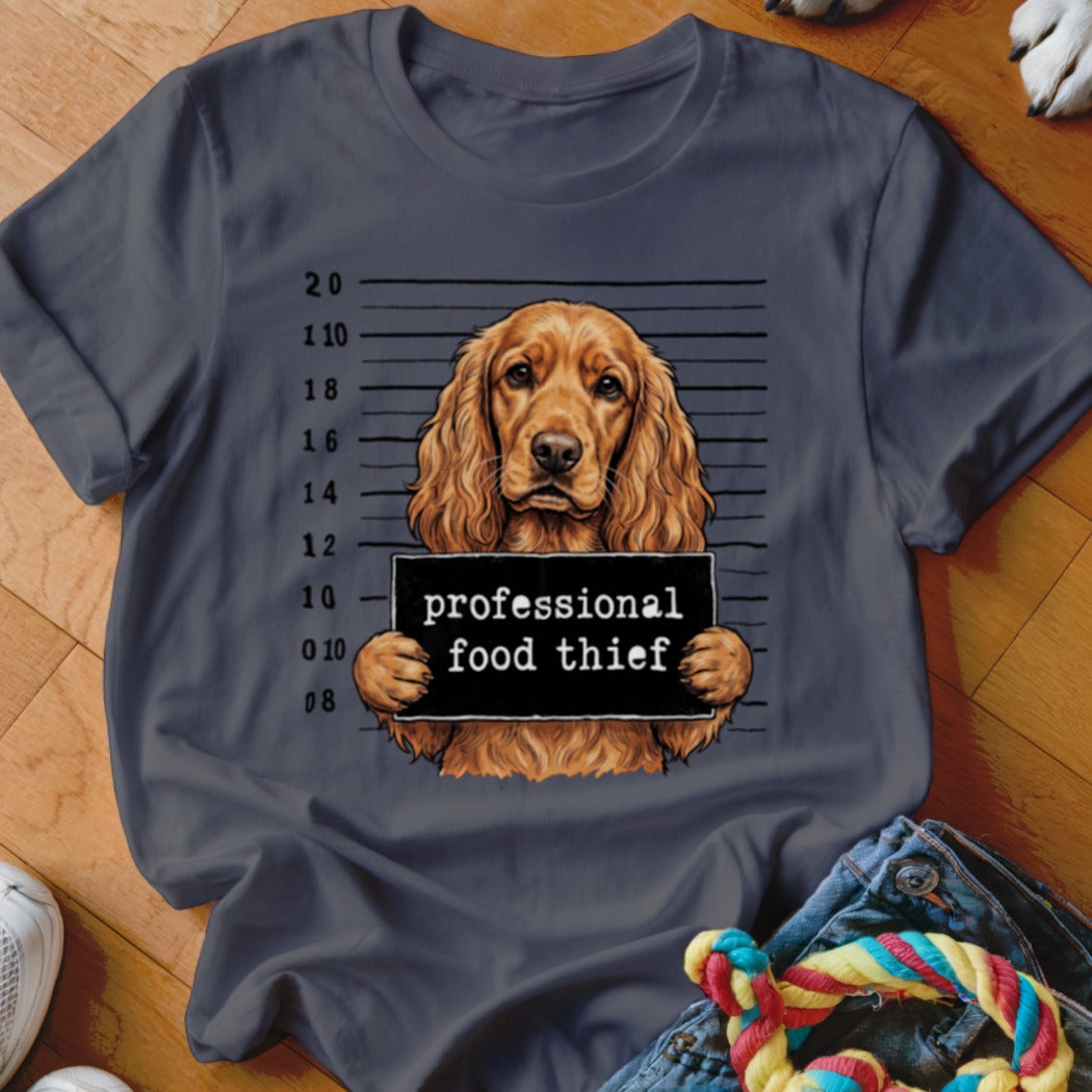 Brown cocker spaniel mugshot with "professional food thief" sign on a grey t-shirt.