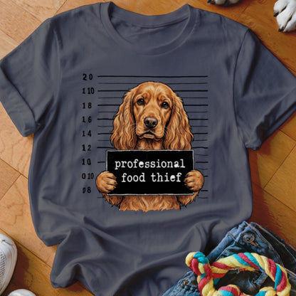 Brown cocker spaniel mugshot with "professional food thief" sign on a grey t-shirt.