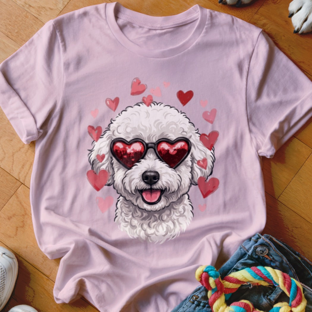 A pink t-shirt featuring a graphic of a white poodle wearing heart-shaped sunglasses surrounded by pink hearts.