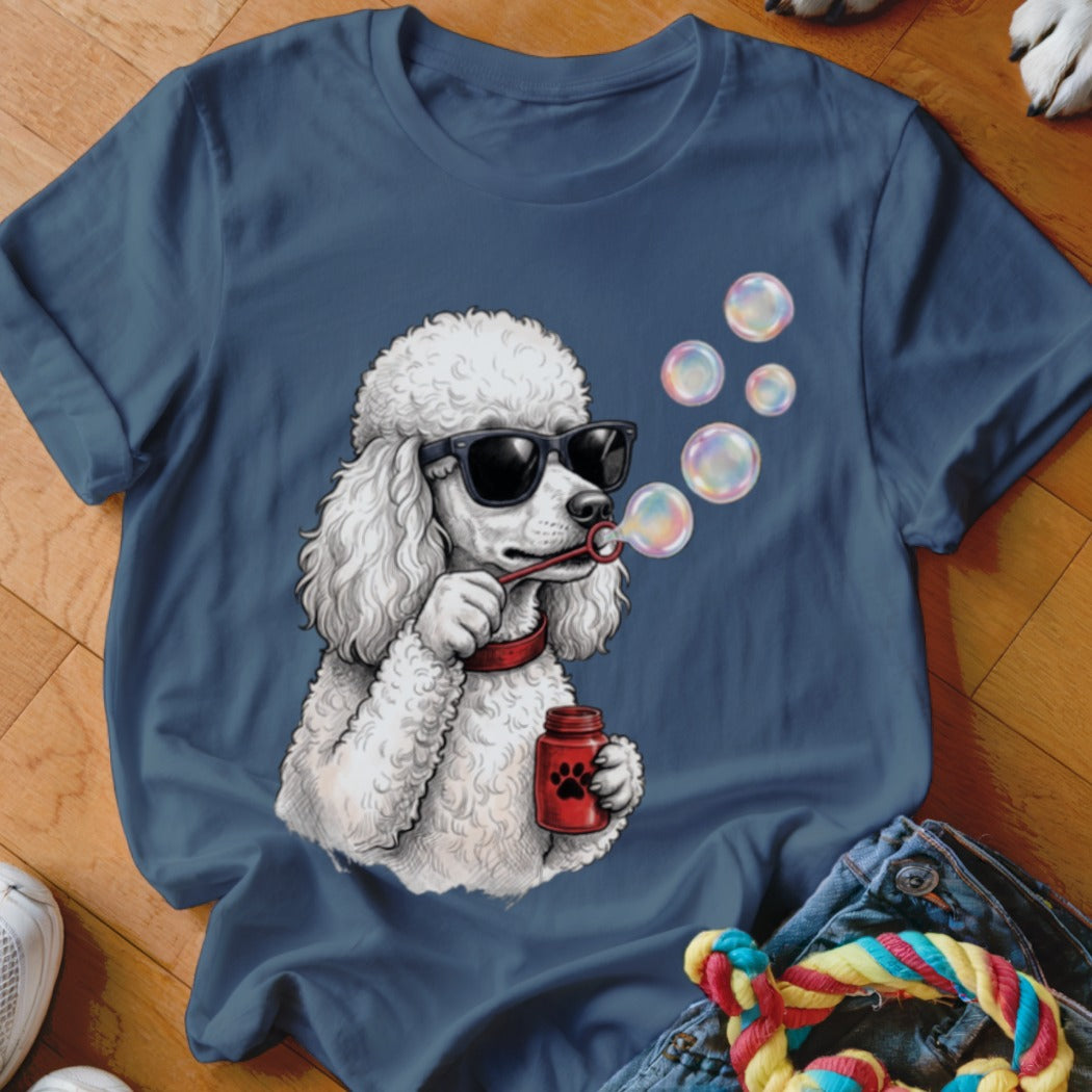 A dark blue t-shirt printed with a graphic of a white poodle wearing sunglasses and blowing soap bubbles.