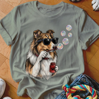 An olive green t-shirt featuring a graphic of a Sheltie dog wearing sunglasses and blowing bubbles.
