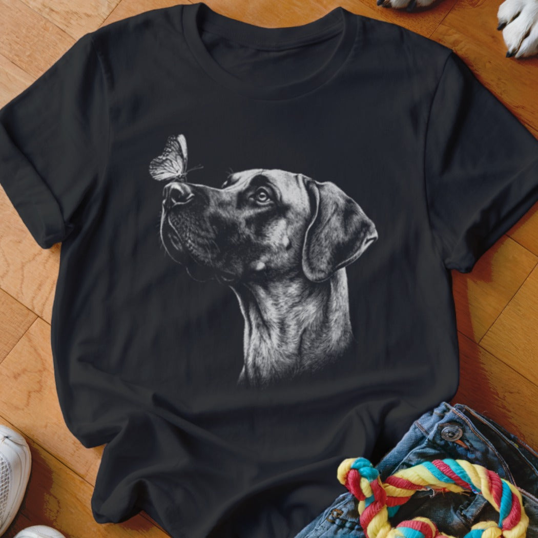 Black t-shirt featuring a white sketch graphic of a dog looking at a butterfly on its nose.