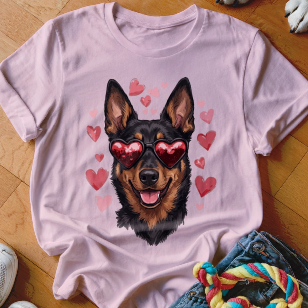 A light pink t-shirt featuring an illustration of a black and tan dog wearing heart-shaped sunglasses, surrounded by pink hearts.