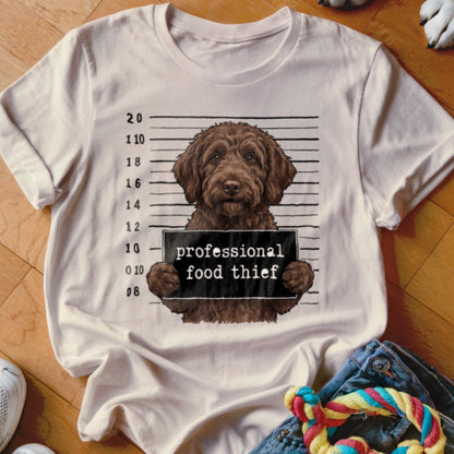Brown dog in mugshot holding a sign that reads "professional food thief".