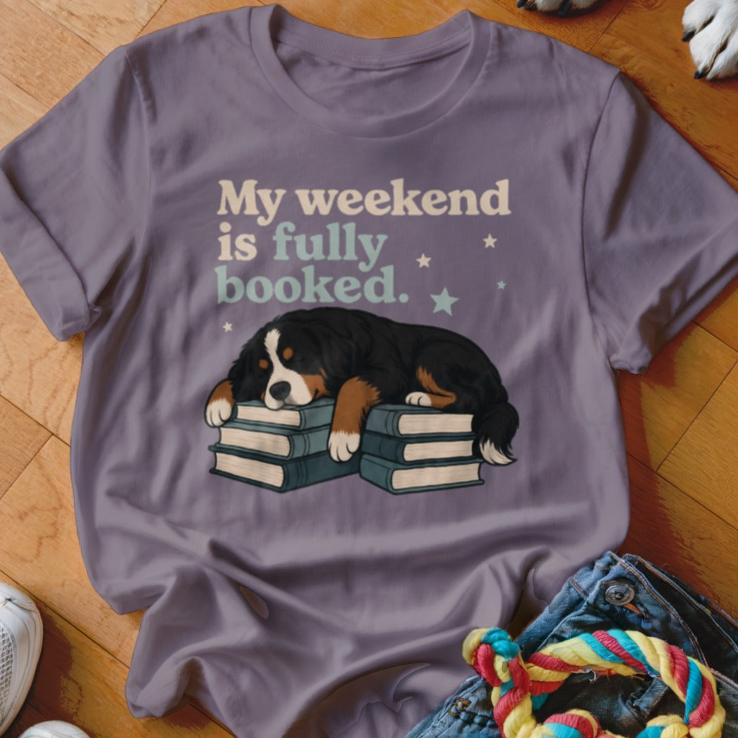 Bernese Mountain Dog sleeping on books with text "My weekend is fully booked."